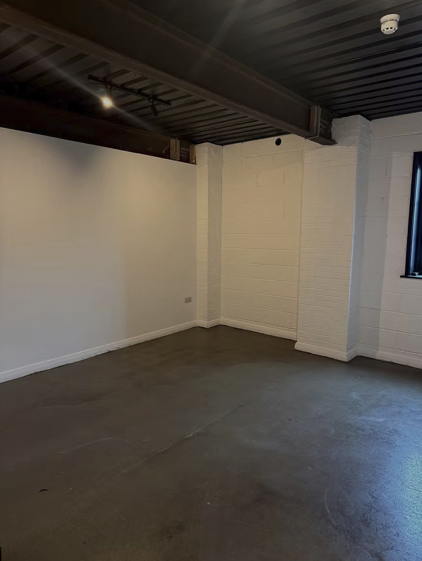 Empty studio room at Harbour House with white walls and dark ceiling beams